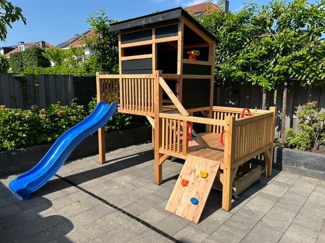 Houten speeltoestel met veranda, klimwand en blauwe glijbaan